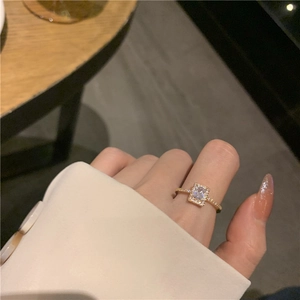 Elegant gold ring with a rectangular zircon and side diamonds on a model's hand