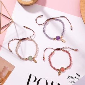 Detail view of handmade woven bracelets with irregular stones and golden charms