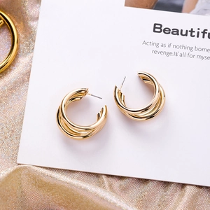 Macro view of triple-layered golden C-shaped hoop earrings on elegant display