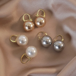 Elegant champagne pearl earrings with gold hooks on a premium silk background