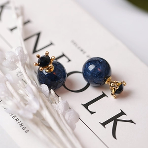 Elegantes pendientes de corona con perlas azul oscuro de textura agrietada en fondo blanco