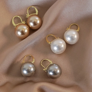 Three pairs of elegant champagne, white, and grey pearl leverback earrings on silk cloth