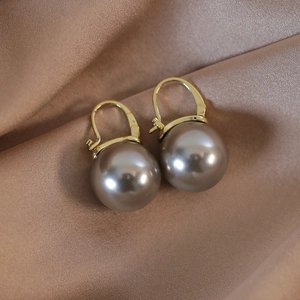 Detailed close-up of champagne pearl drop earrings with elegant golden lever-back hooks