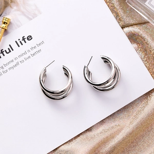 Macro view of silver triple-layered C-shaped stud earrings on white decorative card