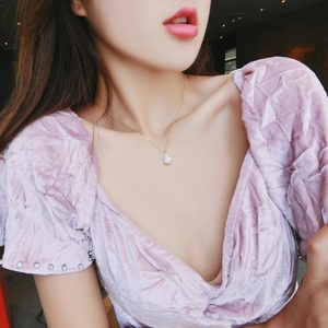 Close-up of elegant gold water drop pendant necklace on model with lavender dress