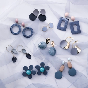 Detailed flat lay of blue-grey geometric earrings set on textured tulle background