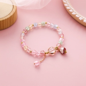 Detail eines bunten Perlenarmbandes mit einem niedlichen Glückskatzen-Anhänger