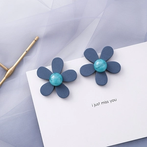 Close-up of blue flower earrings with marble texture centers on white display card