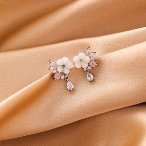 Elegant floral shell earrings with zirconia teardrop crystals on champagne silk background