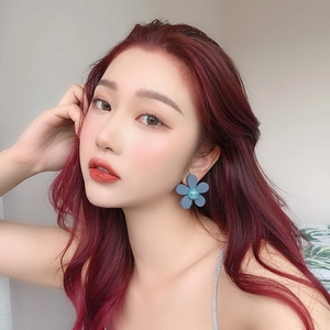 Detail view of blue floral resin earrings with matte finish on a female model