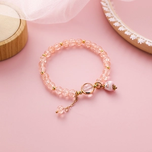 Nahaufnahme von rosa Kristalle Armband mit Keramik-Katze Anhänger und Gold-Details