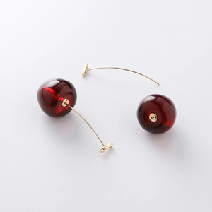 Détail de boucles d'oreilles cerises avec perles rouge foncé et crochets dorés