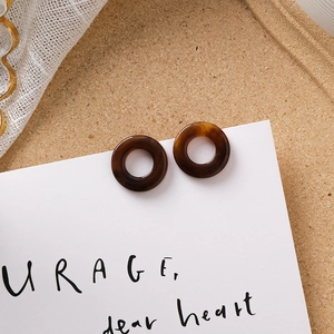 Détail de boucles d'oreilles créoles en résine marbrée café sur fond vintage élégant