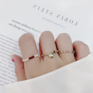Elastic beaded pearl ring set with colorful stones and heart pendant on a magazine