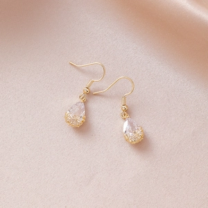 Detail of pear-shaped clear zircon earrings with hollow flower design on silk background