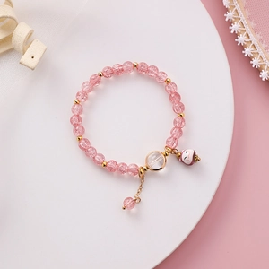 Detail eines rosa Kristallperlen-Armbands mit Glückskatzen-Anhänger auf weißem Ständer