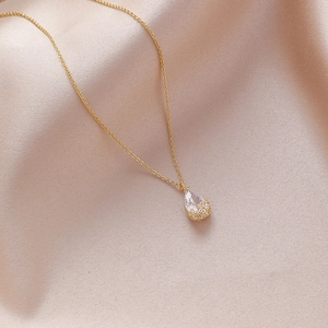 Close-up of elegant gold pear-cut zircon pendant with intricate flower hollow base