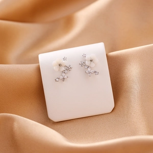Macro detail of shell flower earrings with cubic zirconia on silk background