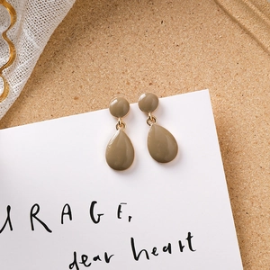 Gros plan détaillé des boucles d'oreilles goutte vert olive avec bordure en métal doré