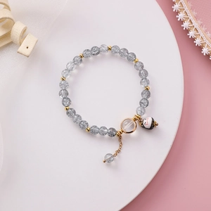 Detail eines süßen Perlenarmbands mit grauem Quarz und Glückskatzen-Anhänger