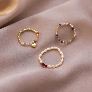 Detailed view of elastic beaded rings with pearls, heart charms and colorful stones