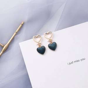 Detail of gold heart earrings with dark blue enamel pendants on white card background