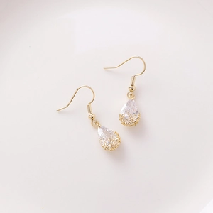 Detail of drop-shaped zircon earrings with golden floral hollow base and crystal pendants