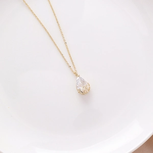 Close-up of golden necklace with water-drop zircon pendant and hollow flower base