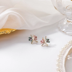 Detail of floral earrings featuring pink and green petals with pearls and crystals