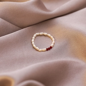 Detail of baroque pearl elastic ring with red faceted crystal beads on purple silk