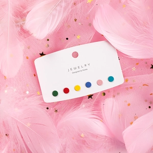 Detail of 6-pair colorful round stud earring set on white display card with pink feathers