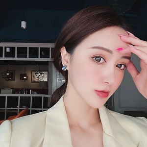 Close-up of model wearing elegant square blue gemstone stud earrings with gold plating