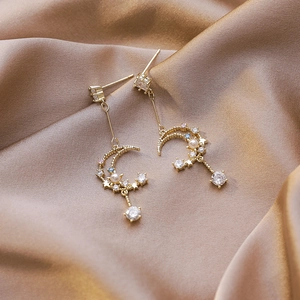 Detail of moon tassel earring with colorful zircons and pearls on champagne silk
