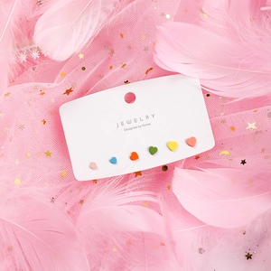 Close-up of six-piece matte heart earring set on jewelry card with pink feather background