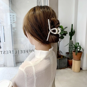 Eleganter großer Perlen-Haarclip für Damen, am Haar in einem stilvollen Café gezeigt