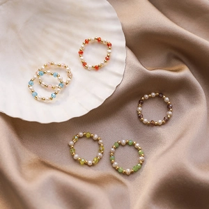 Handmade beaded rings with freshwater pearls and colorful crystals on silk background