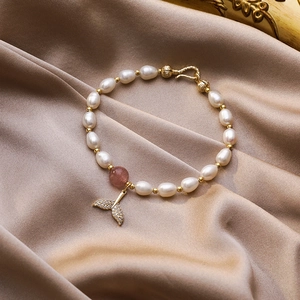 Dettaglio del bracciale di perle con ciondolo a coda di sirena scintillante e cristallo rosa