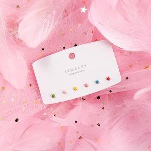 Close-up of colorful matte star stud earrings set displayed on pink feather background