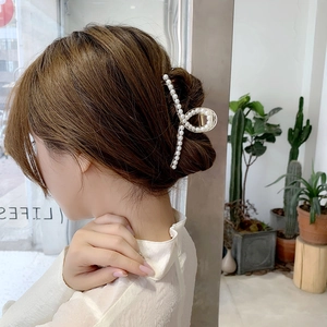 Eleganter goldener Haarklammer mit weißen Perlen gestylt im Haar einer Frau im Zimmer