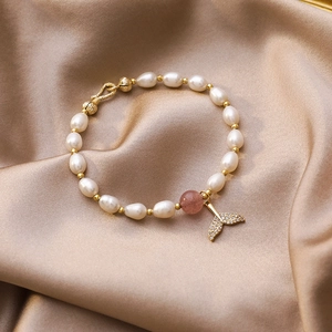 Primo piano del bracciale di perle con ciondolo a forma di coda di sirena dorata lucida