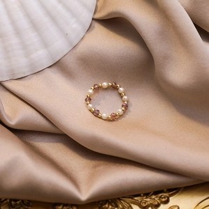 Detailed close-up of handmade pearl ring with purple crystals on silk fabric