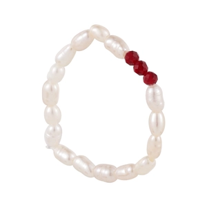 Macro detail of baroque pearl and faceted red crystal elastic ring on white background