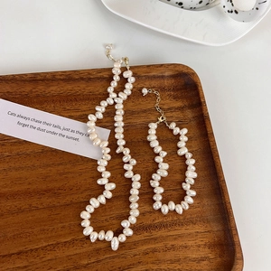 Ensemble collier et bracelet en perles d'eau douce baroques sur un plateau en bois