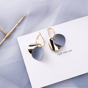 Detailed macro view of gold hoop earrings with blue-grey matte and mirror metal charms