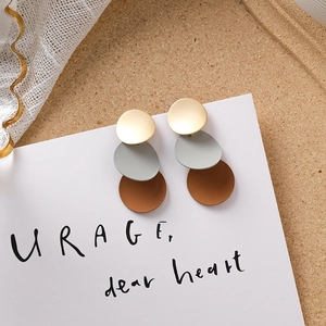 Gros plan de boucles d'oreilles géométriques mates avec disques à trois couches bicolores