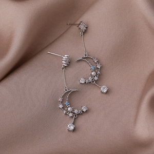 Detail of moon tassel earring with colorful zircon stones on champagne satin background