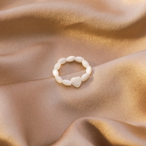 Beaded heart shell ring with translucent white stones on champagne silk background