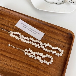 Vue détaillée du collier et bracelet en perles baroques dans un plateau en bois