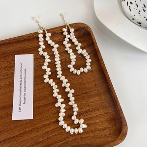 Parure collier et bracelet en perles d'eau douce baroques sur un plateau en bois vintage