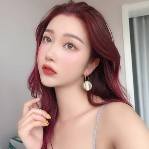 Close-up of elegant gold circular drop earrings worn by a model with red hair